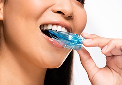 Nose-to-neck view of woman inserting blue transparent nightguard