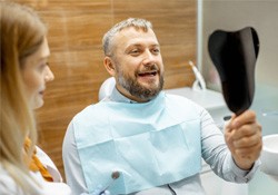 a patient looking at his dental restorations using a mirror