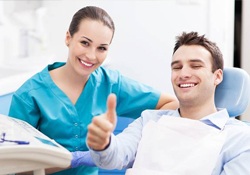 Smiling man in dental chair giving thumbs up