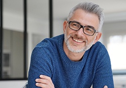 older man smiling with arms crossed