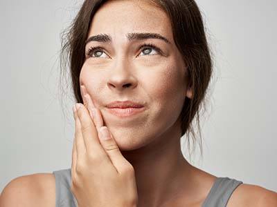 Woman with a toothache in Green Hills holding her mouth