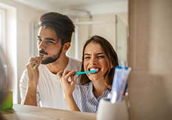 Couple brushing teeth as recommended by their Green Hills emergency dentist