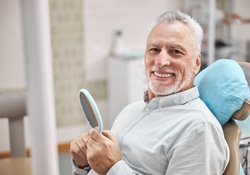 An older man smiles after learning about dental implant care in Green Hills