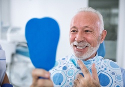 An older man looking at his dental implants in Green Hills