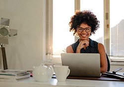 a smiling person working on their laptop