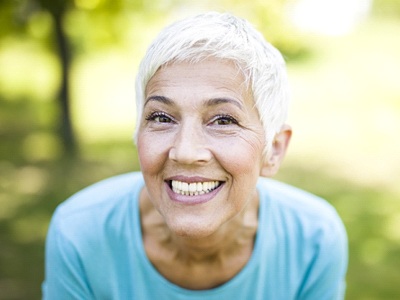 older woman smiling with implant dentures in Green Hills 