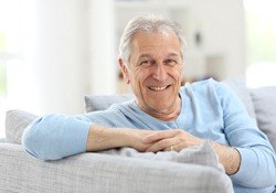  older man sitting on a couch and smiling