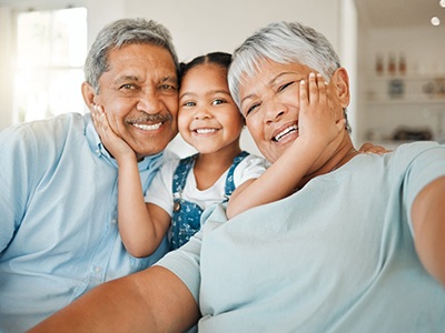 Grandparents smiling with their grandchild after visiting a MetLife dentist in Green Hills