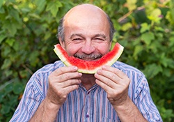 Man eating watermelon to lower risk of dental emergencies in Nashville
