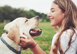 person smiling and playing with dog