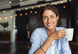 person smiling and drinking a cup of coffee