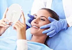A woman smiling at her teeth in a mirror