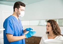 A dentist explaining how dental implants work to a female patient with a missing tooth