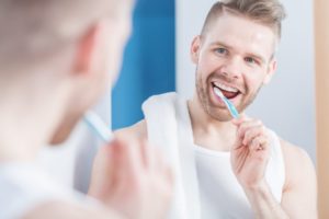 man smiling while brushing teeth