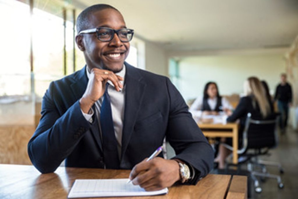 Man smiling while attending a meeting in his job office.