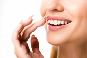 Woman smiling and gesturing towards veneers.