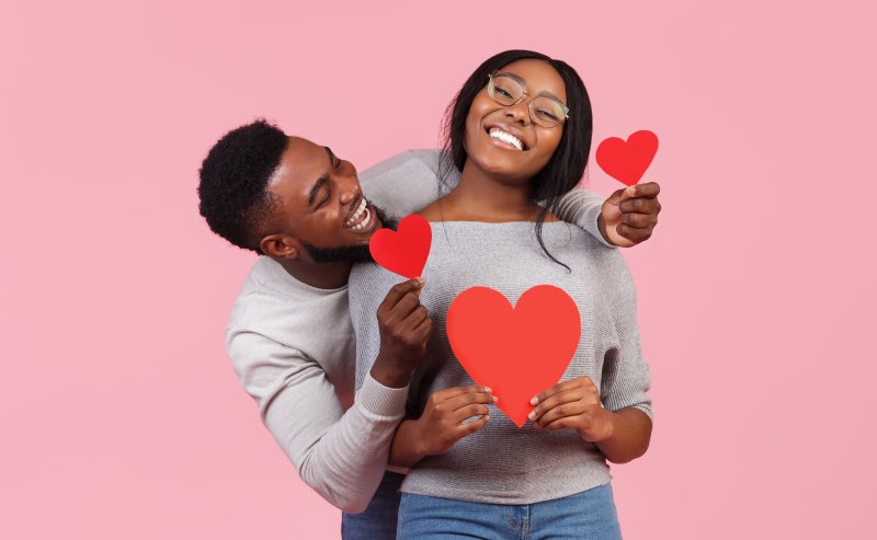 An African American couple holding red Valentine hearts